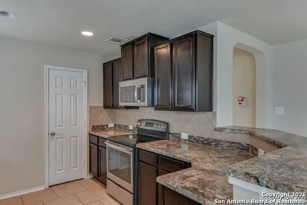 a kitchen with stainless steel appliances granite countertop a stove a sink and a microwave