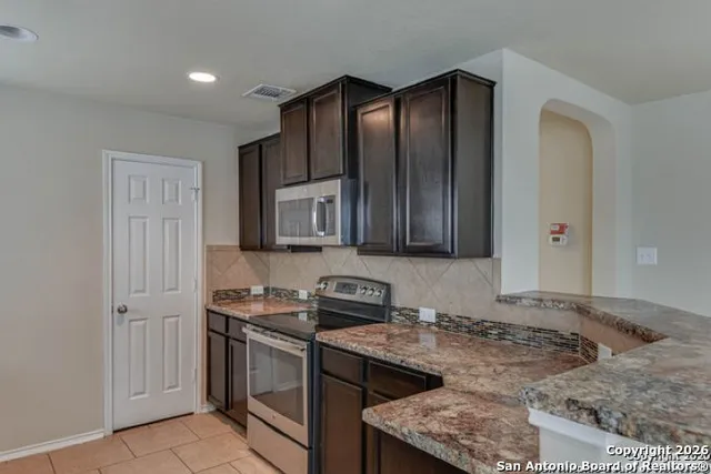 a kitchen with stainless steel appliances granite countertop a stove a sink and a microwave