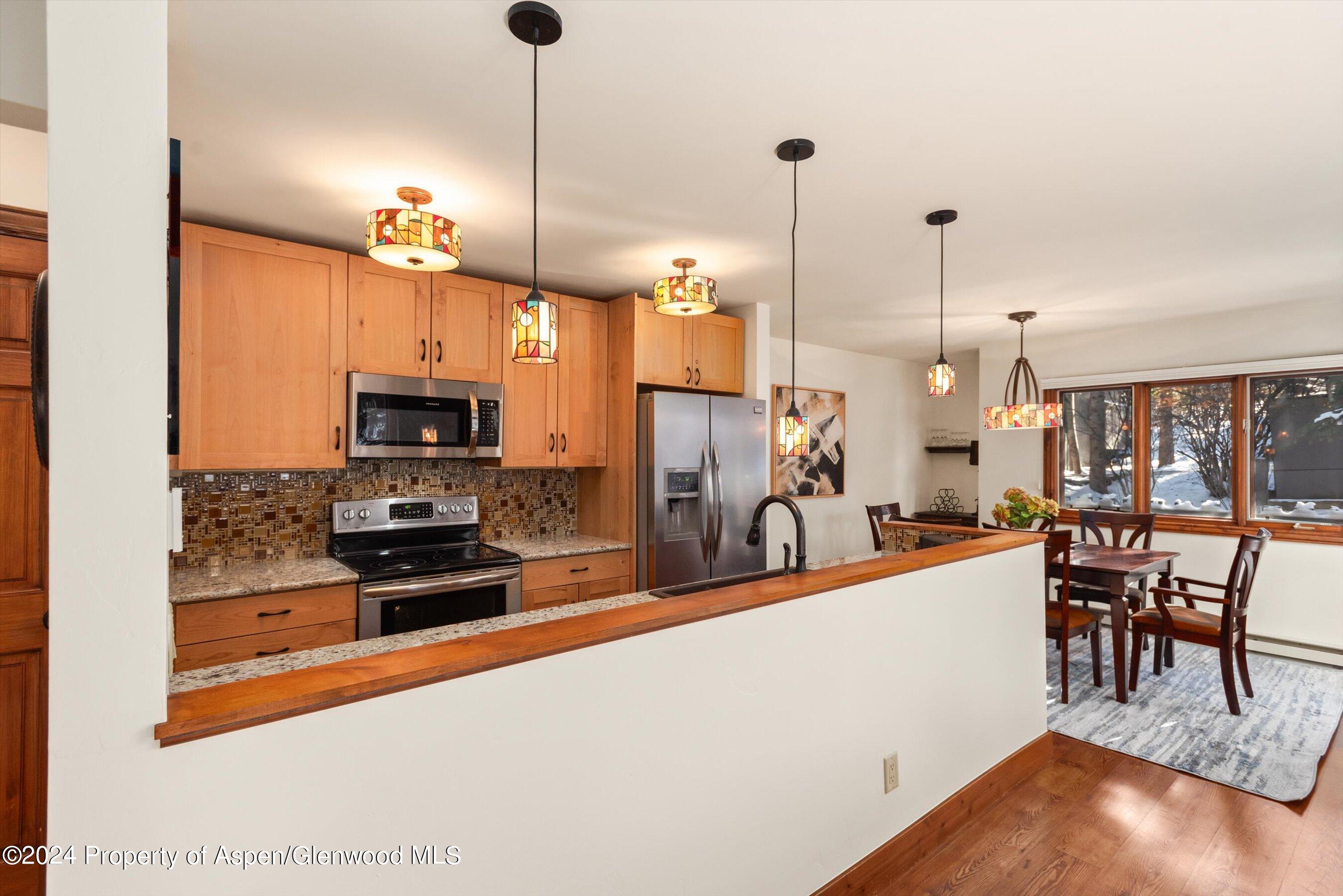374 Meadow Ranch Road Snowmass Village, CO 81615 - Photo 7 of 22 a kitchen with stainless steel appliances a stove a sink a dining table and chairs