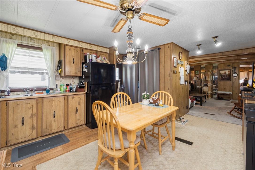 35157 Center Ridge Road, Unit 117 North Ridgeville, OH 44039 - Photo 14 of 21 Dining space featuring wooden walls, ceiling fan, light wood finished floors, and a chandelier