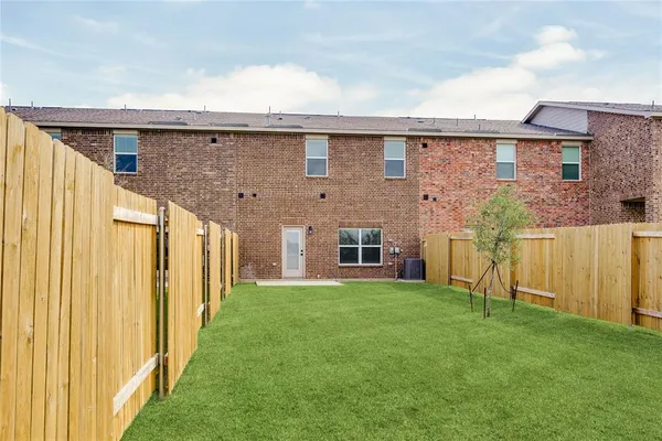 a backyard of a house with plants and wooden fence
