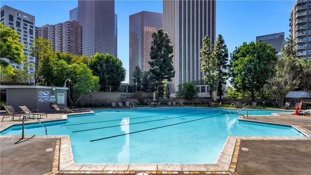 a view of swimming pool with outdoor seating and trees in the background