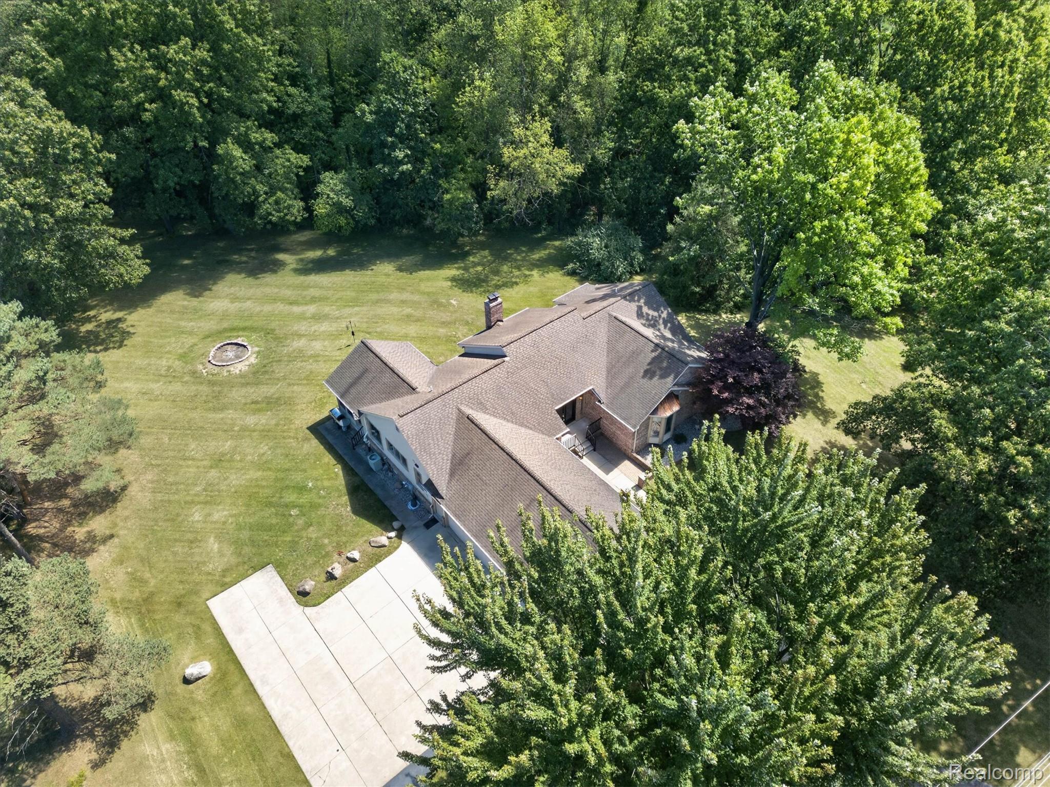 4037 Chilson Road Howell, MI 48843 - Photo 55 of 69 Expansive property featuring a paved driveway, a large private yard with mature trees, and a built-in fire pit