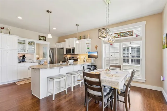 a kitchen with stainless steel appliances a dining table chairs and wooden floor