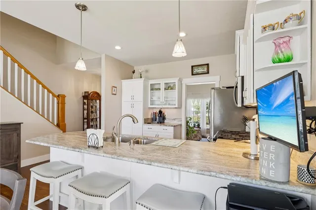 a room with stainless steel appliances kitchen island granite countertop a table chairs in it and wooden floor