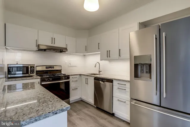 a kitchen with stainless steel appliances granite countertop a refrigerator stove and sink