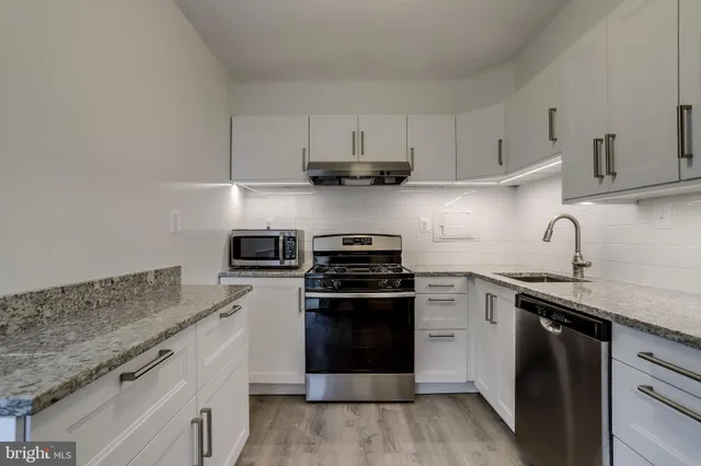 a kitchen with granite countertop white cabinets and stainless steel appliances