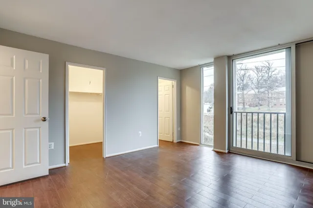 an empty room with wooden floor and windows