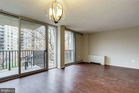 a view of an empty room with wooden floor and windows