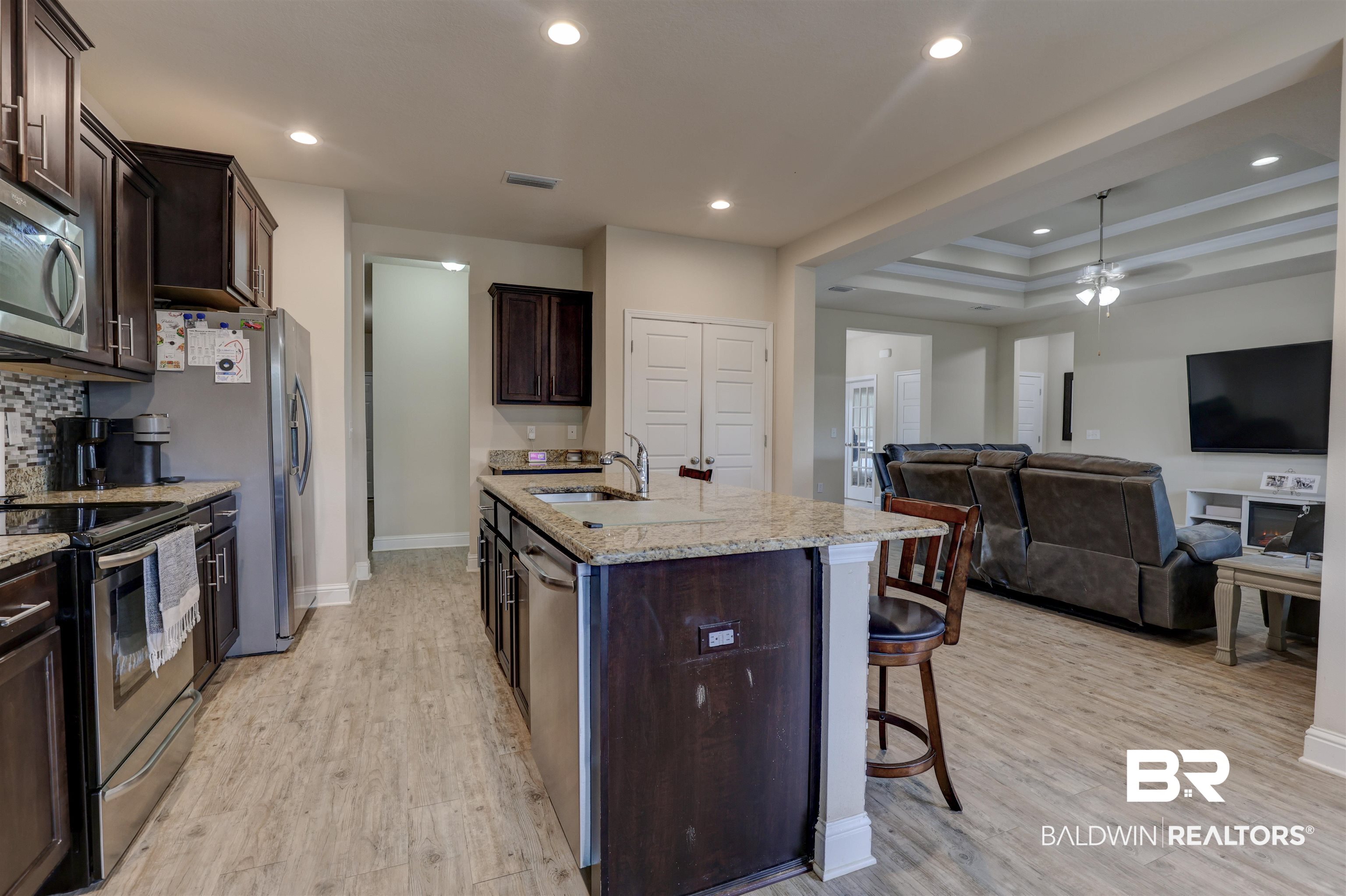 21902 Yosemite Boulevard Fairhope, AL 36532 - Photo 8 of 32 Kitchen with light hardwood / wood-style flooring, dark brown cabinetry, stainless steel appliances, and a raised ceiling
