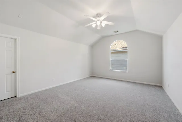 an empty room with a chandelier fan and a window