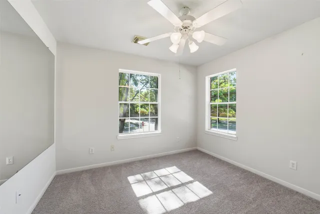 an empty room with windows and fan