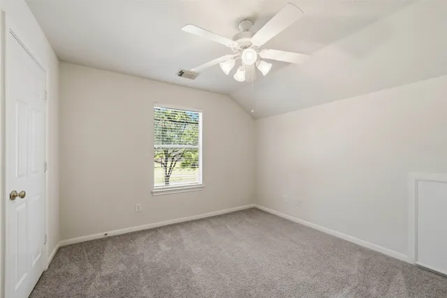 an empty room with windows and fan