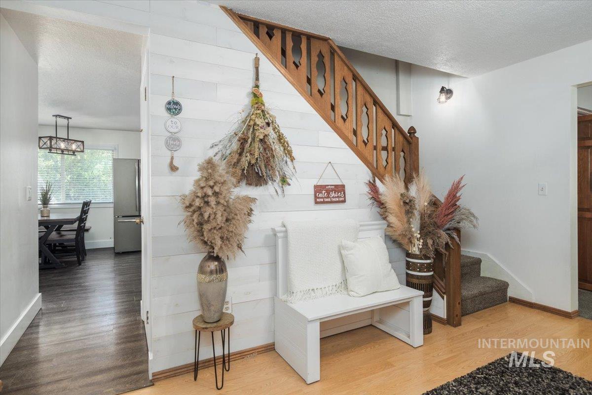 1401 Chokecherry Drive Pocatello, ID 83204 - Photo 3 of 46 Inviting entryway featuring a white shiplap accent wall, wood-finish flooring, and a natural wood staircase with intricate balusters