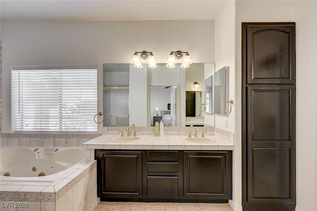 2955 El Camino Road Las Vegas, NV 89146 - Photo 54 of 99 Bathroom featuring double vanity, light tile patterned flooring, a jetted tub, connected bathroom, and a shower stall