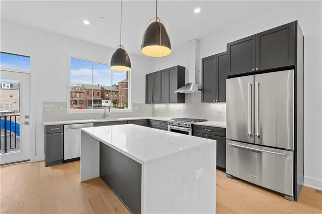 a kitchen with stainless steel appliances granite countertop a refrigerator a sink a stove and a refrigerator