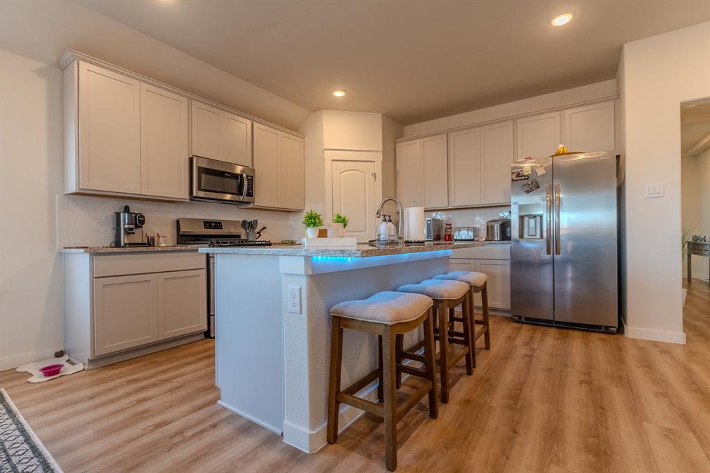1571 Gentle Night Drive Forney, TX 75126 - Photo 2 of 15 a kitchen with stainless steel appliances granite countertop a sink a stove a refrigerator cabinets and a dining table