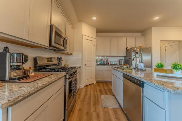 a kitchen with stainless steel appliances granite countertop a stove a sink and a microwave