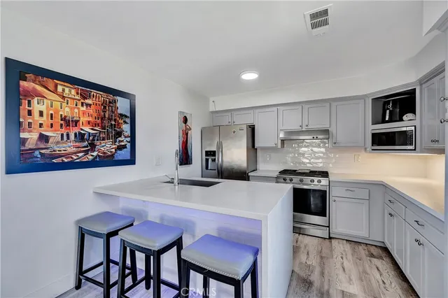 a kitchen with stainless steel appliances granite countertop a stove a refrigerator a sink a dining table and chairs with wooden floor