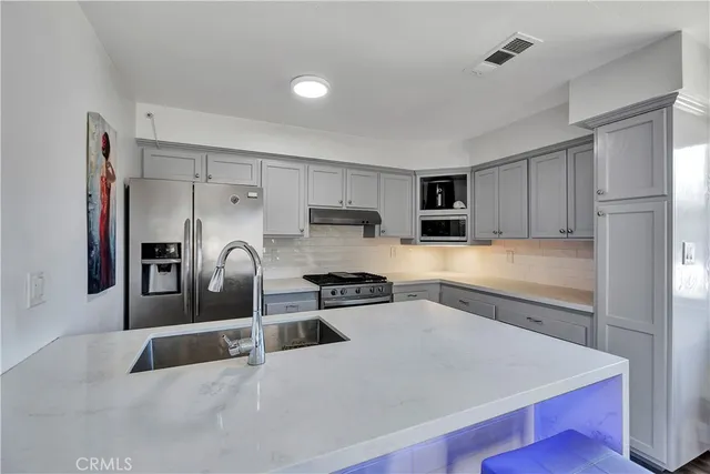 a kitchen with stainless steel appliances granite countertop a refrigerator a stove and a sink with wooden floor