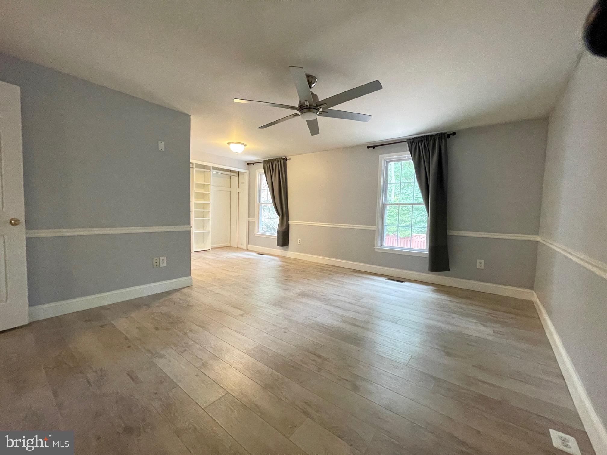 308 Crescendo Way Silver Spring, MD 20901 - Photo 17 of 26 an empty room with wooden floor ceiling fan and windows