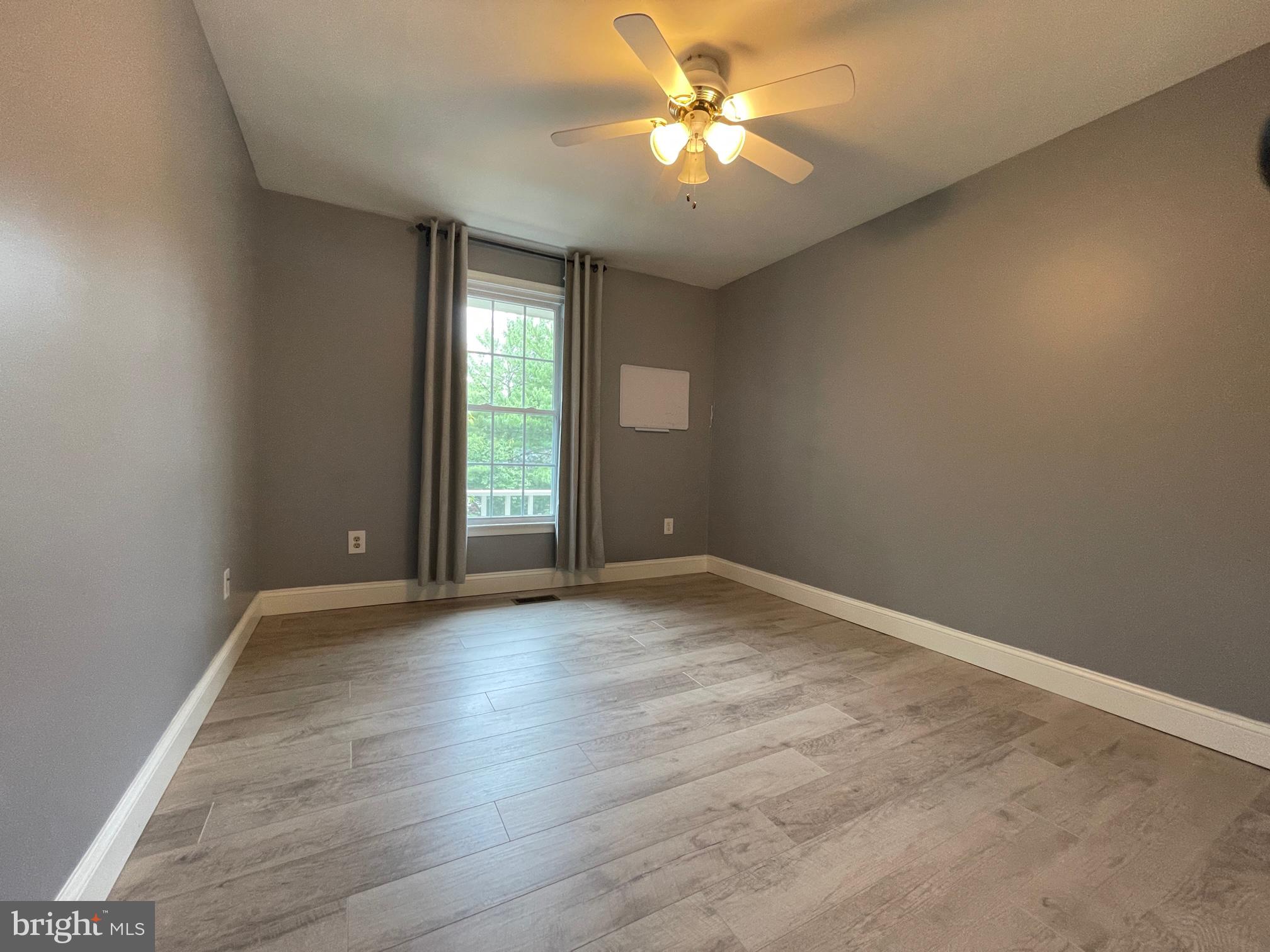308 Crescendo Way Silver Spring, MD 20901 - Photo 24 of 26 an empty room with wooden floor fan and windows