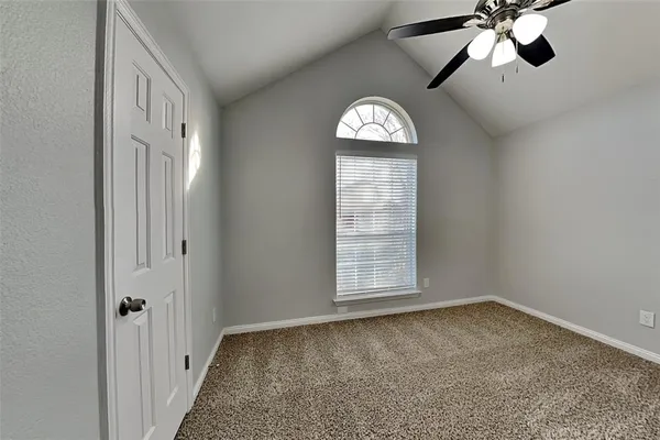 an empty room with windows and ceiling fan