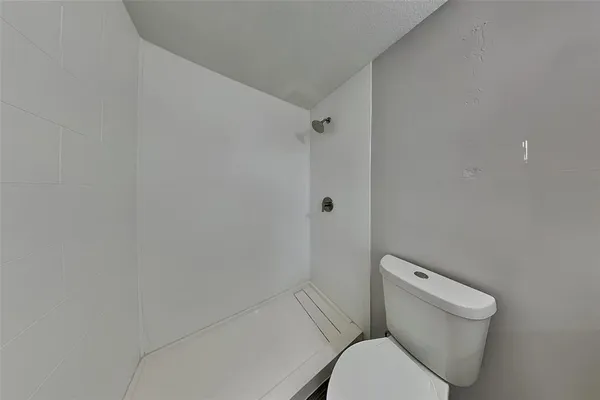 a white toilet sitting next to a shower