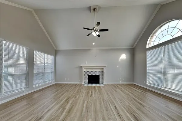 an empty room with wooden floor fan and windows