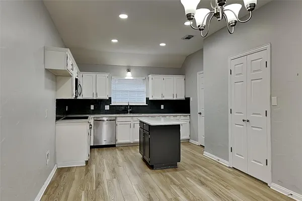 a kitchen with kitchen island granite countertop a sink cabinets and wooden floor