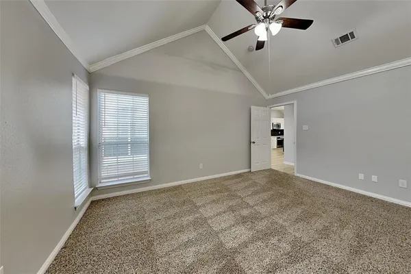 an empty room with chandelier fan and windows