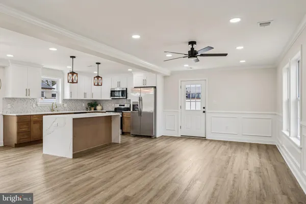 a large kitchen with granite countertop a stove top oven a sink dishwasher and a refrigerator with wooden floor