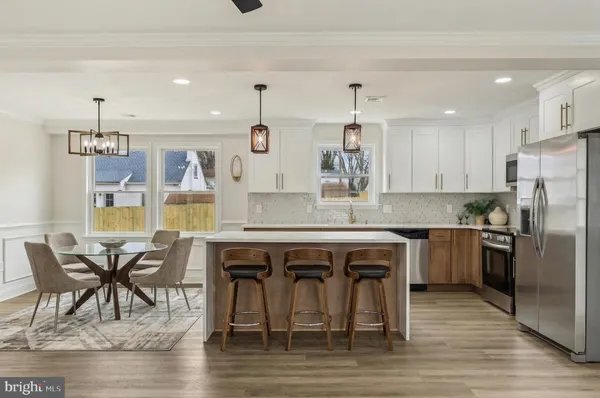 a kitchen with stainless steel appliances granite countertop a table chairs stove and refrigerator