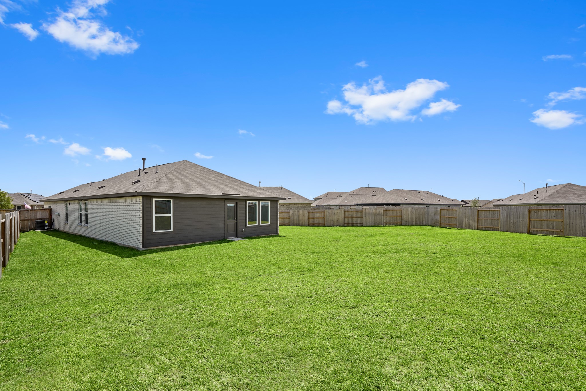 26931 Feather Reed Drive Katy, TX 77493 - Photo 14 of 16 A wider angle of the fully fenced backyard reveals an expansive lawn layout and dedicated side yard space, perfect for outdoor activities.