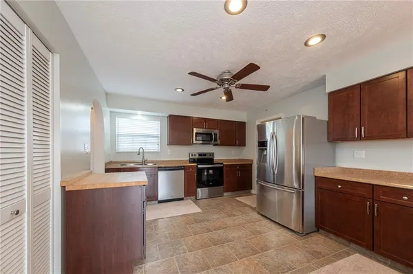a kitchen with stainless steel appliances granite countertop a refrigerator a sink a stove with cabinets