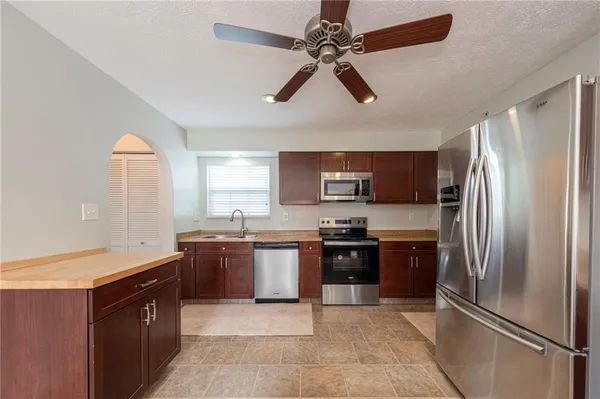 a kitchen with stainless steel appliances granite countertop a refrigerator a sink a stove top oven and a refrigerator