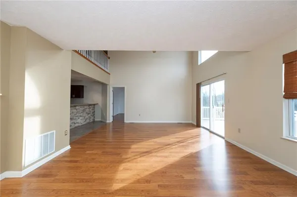 a view of an empty room with window and wooden floor