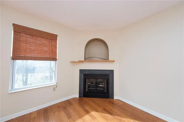 a view of an empty room with a fireplace and a window