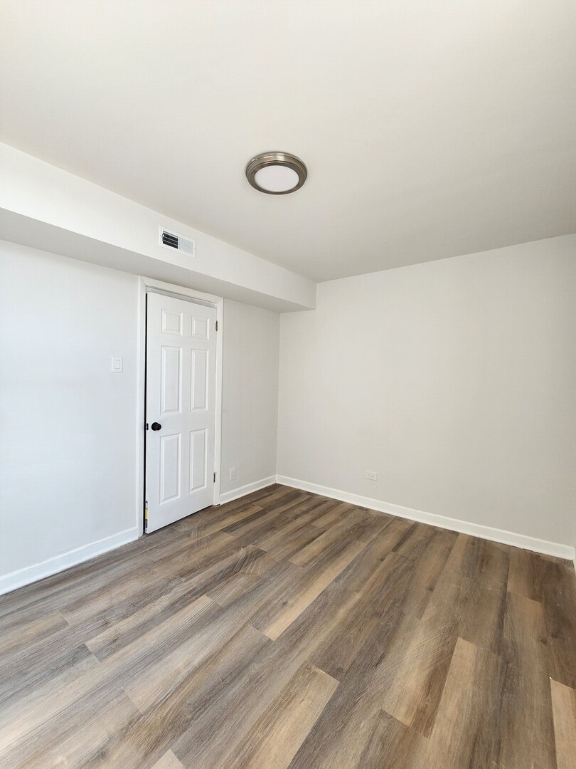 8900 South Normal Avenue Chicago, IL 60620 - Photo 15 of 28 a view of an empty room with wooden floor and a window