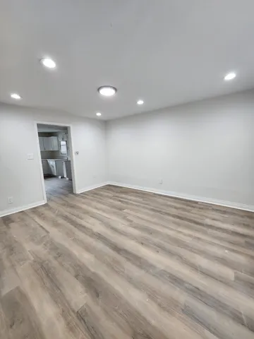 an empty room with wooden floor and natural light