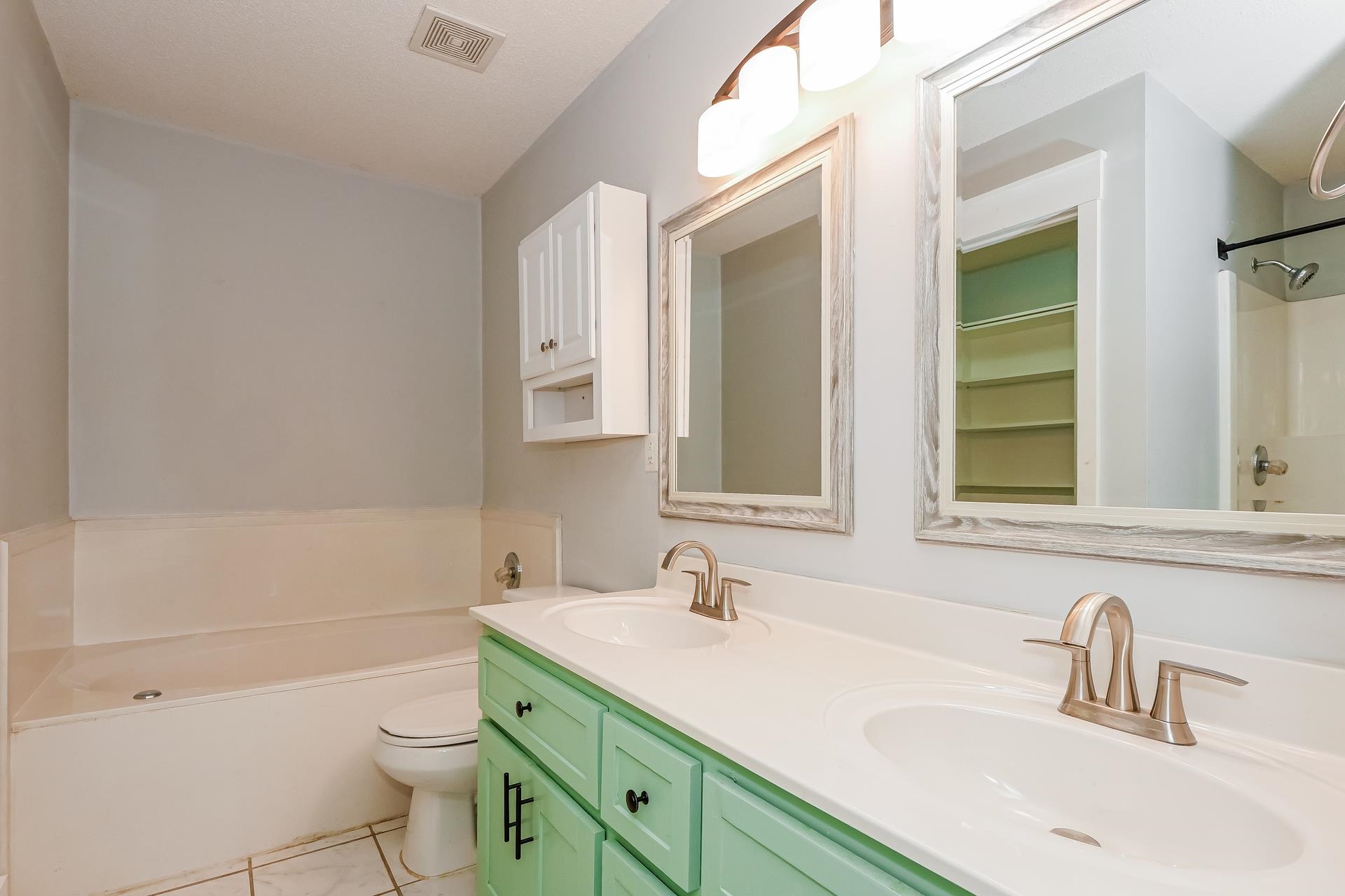 188 David Reed Drive Munford, TN 38058 - Photo 11 of 20 Bathroom featuring a dual vanity with a light green cabinet, white countertops, two framed mirrors, and brushed nickel fixtures