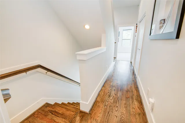 a view of a hallway with wooden floor and staircase