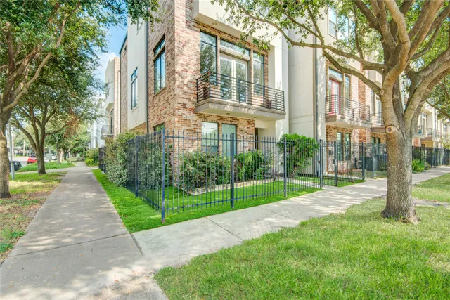 a view of a brick house with a yard and large trees