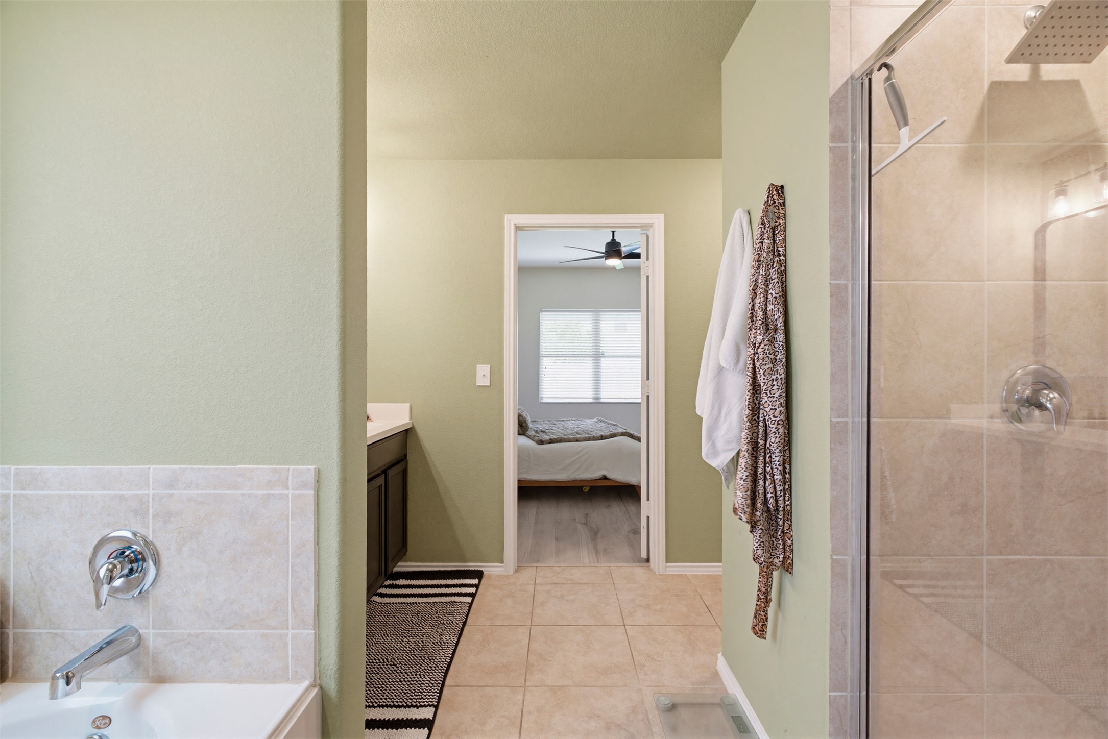 5705 Southerner Way Austin, TX 78747 - Photo 12 of 22 A tranquil primary bathroom features a tiled shower and soaking tub, with a peek into a restful bedroom.