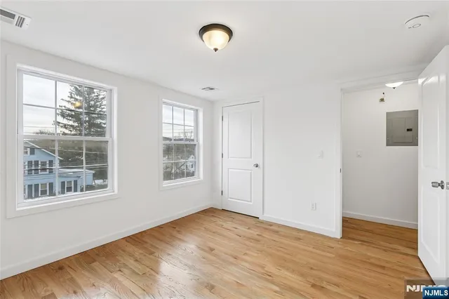 a view of an empty room with wooden floor and windows
