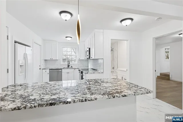 a large kitchen with kitchen island sink refrigerator and cabinets