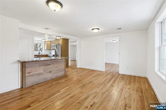 a view of kitchen and empty room with wooden floor