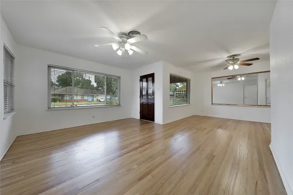 a view of an empty room with window and wooden floor