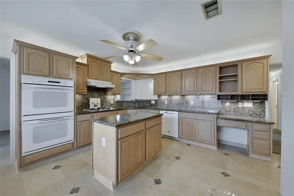 a kitchen with kitchen island granite countertop appliances cabinets and a counter space