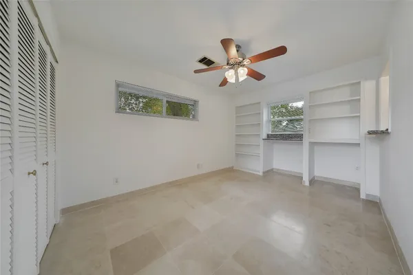an empty room with closet and windows